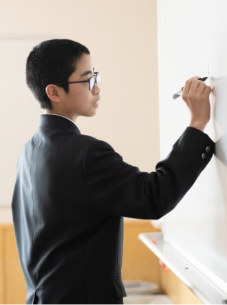 ホワイトボードに書き込み中の生徒